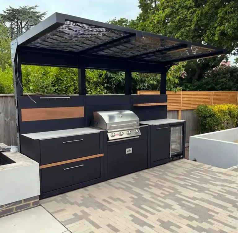 Modern outdoor kitchen with a barbecue grill, storage drawers, a drinks fridge, and a stylish veranda featuring a slatted roof design.